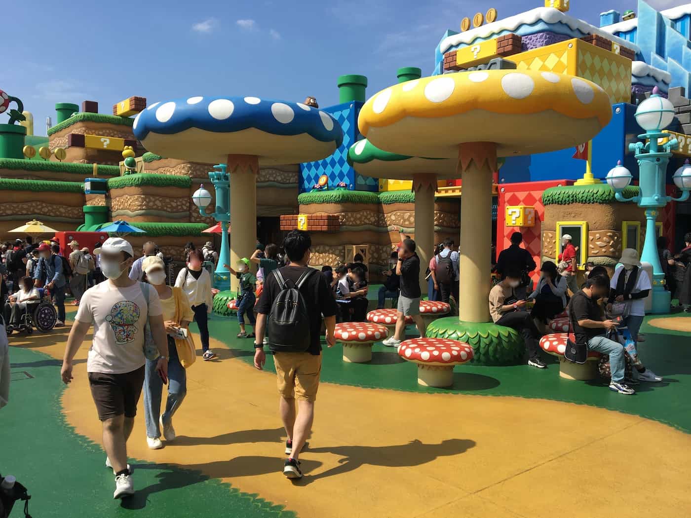 Visitors relaxing under the shade of giant mushroom structures at Super Nintendo World.