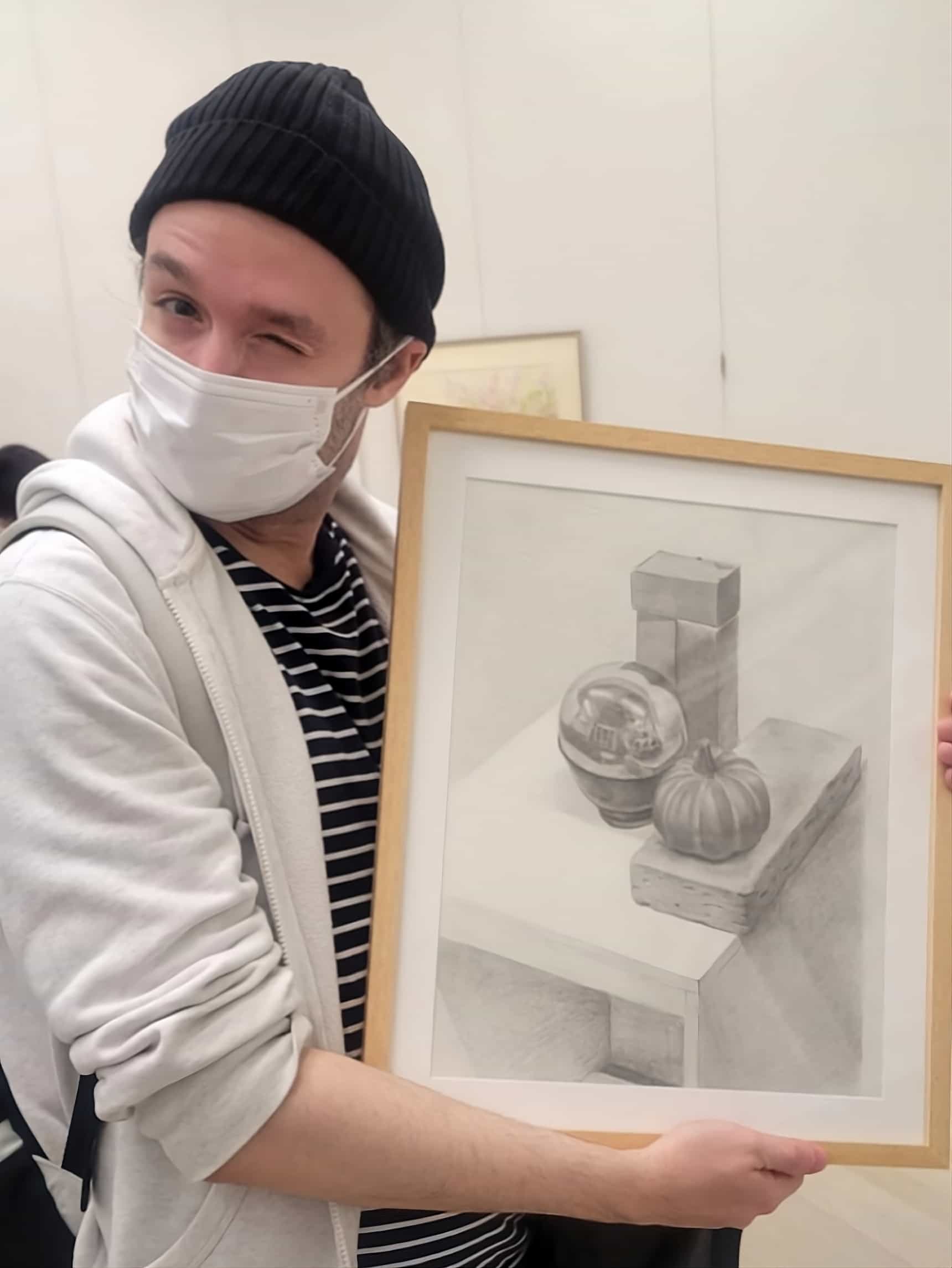 Alessandro Cuzzocrea holding his graphite still life artwork at the atelier art exhibition