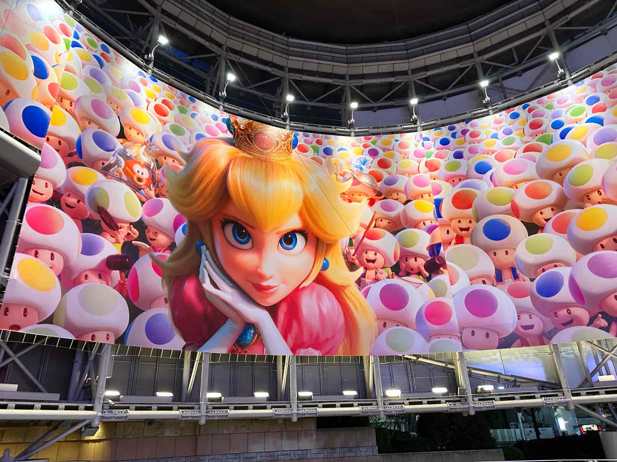 Large billboard featuring Princess Peach from the Super Mario series, surrounded by a multitude of colorful Toads, situated just outside TOHO Cinemas Roppongi Hills