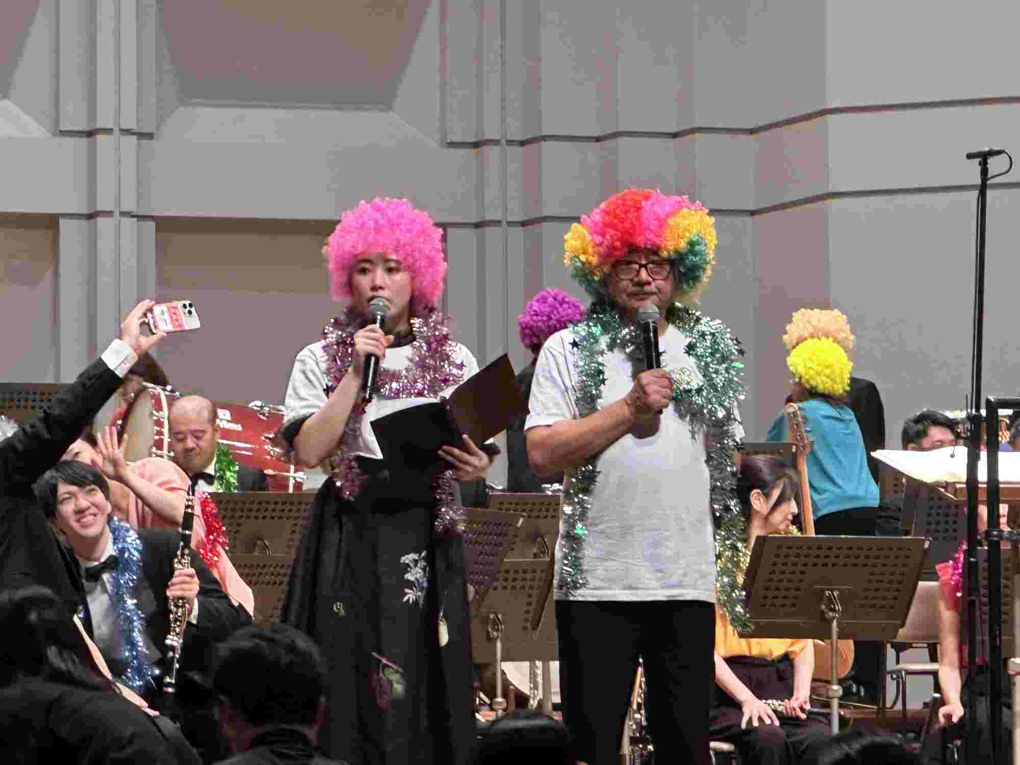 Nobuo Uematsu and Mami Yamashita on stage at the BRA★BRA FINAL FANTASY 2024 concert, wearing colorful wigs and tinsel as they entertain the audience