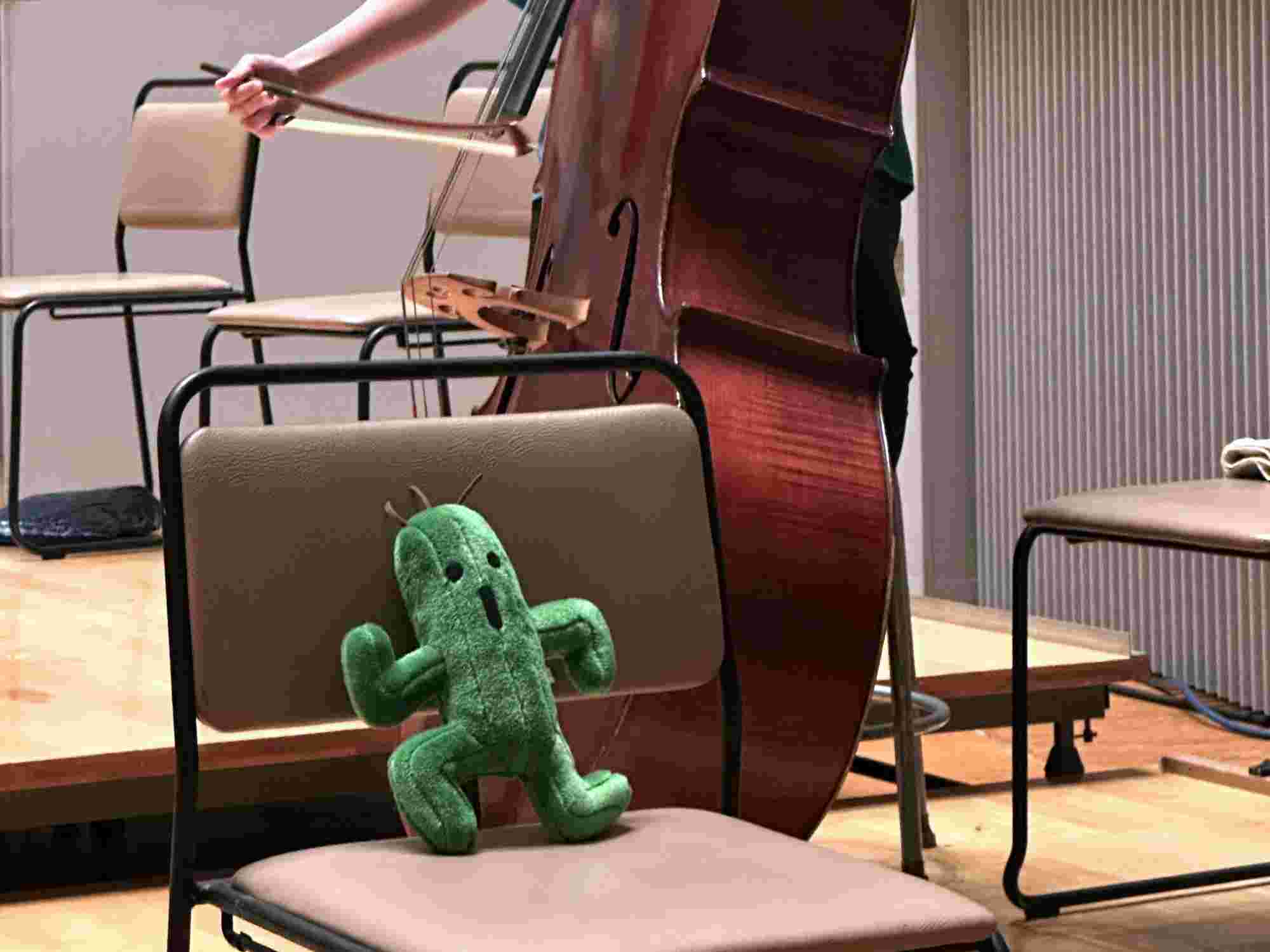 Plush Cactuar toy placed on a chair on stage next to a double bass at the BRA★BRA FINAL FANTASY 2024 concert