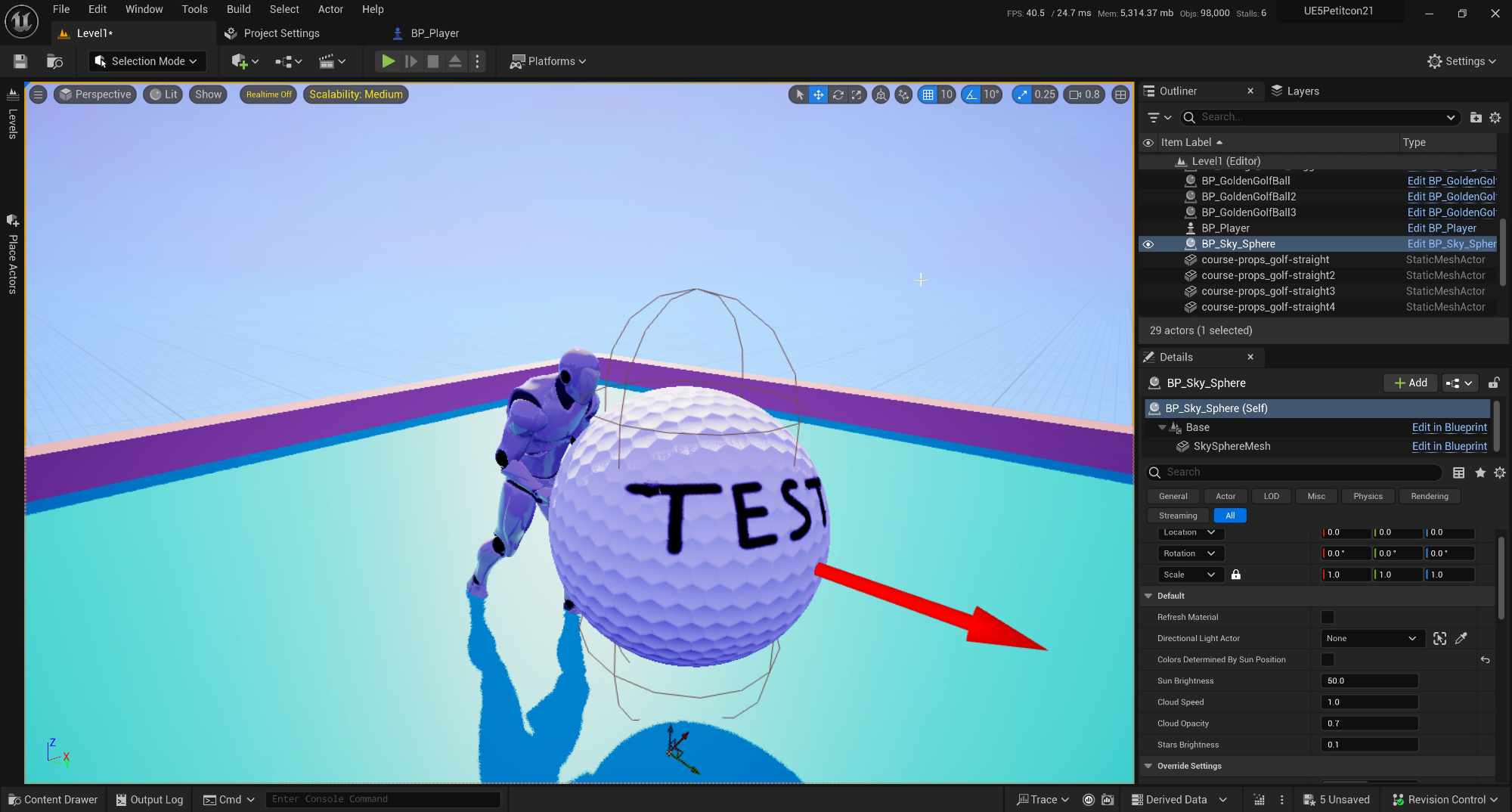 Unreal Engine editor window showing a 3D scene with a humanoid character pushing a giant golf ball labeled 'TEST.' A red arrow points to the ball, and the skybox is a gradient of blue and purple. The Outliner and Details panels are visible on the right side of the screen, displaying scene objects and their properties